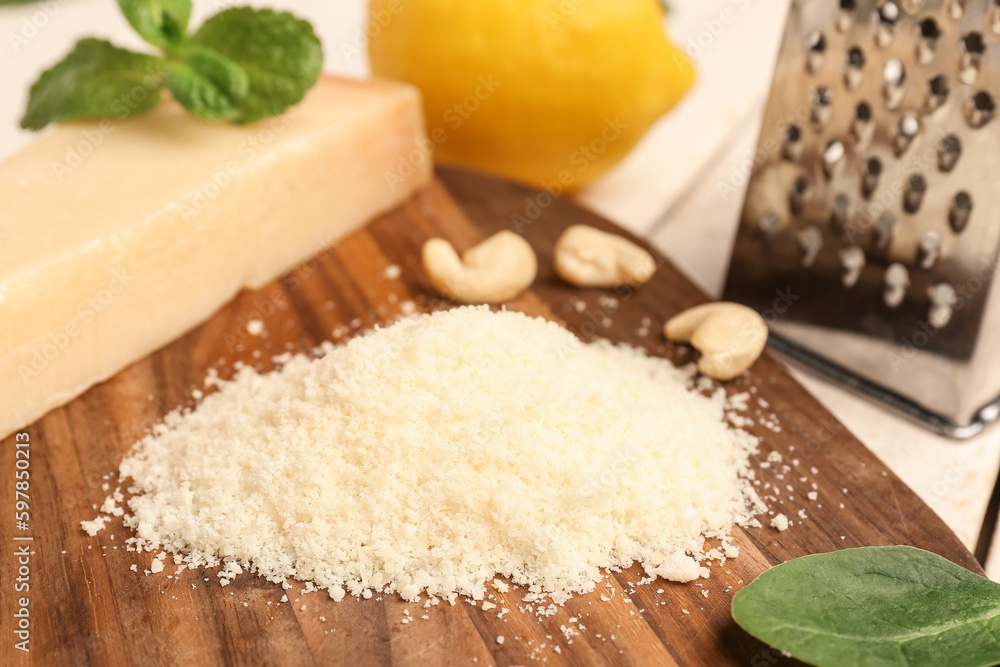 Board with tasty grated Parmesan cheese on light wooden background, closeup