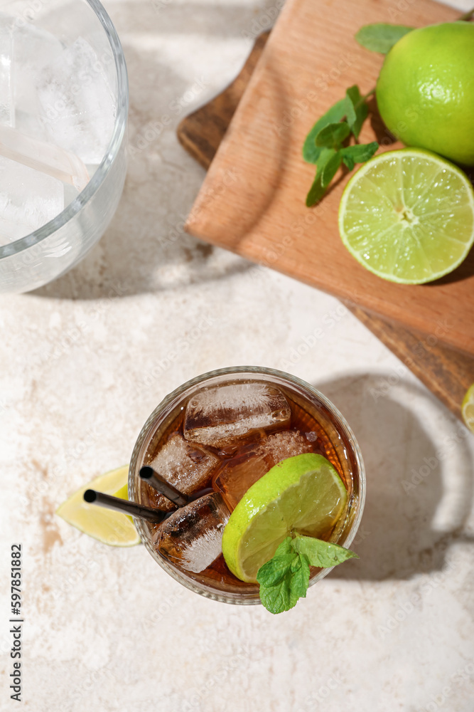 Glass of tasty Cuba Libre cocktail on light background