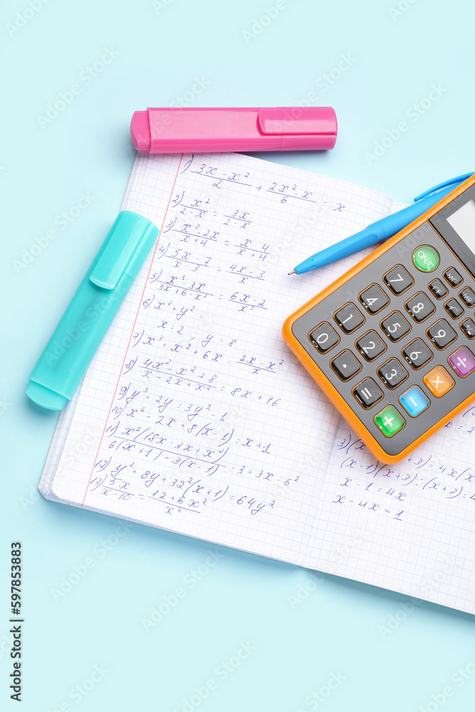 Copybook with maths formulas, calculator and stationery on blue background