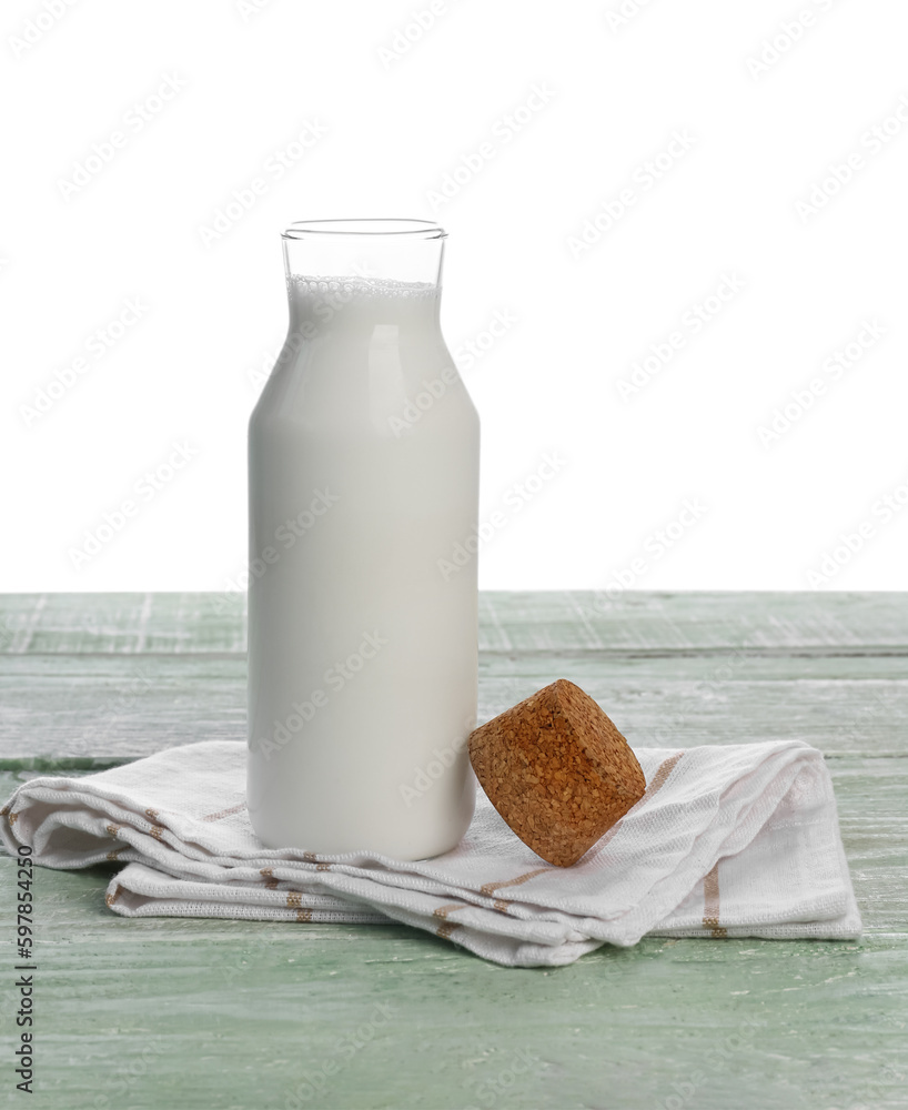 Opened glass bottle of milk on green wooden table against white background