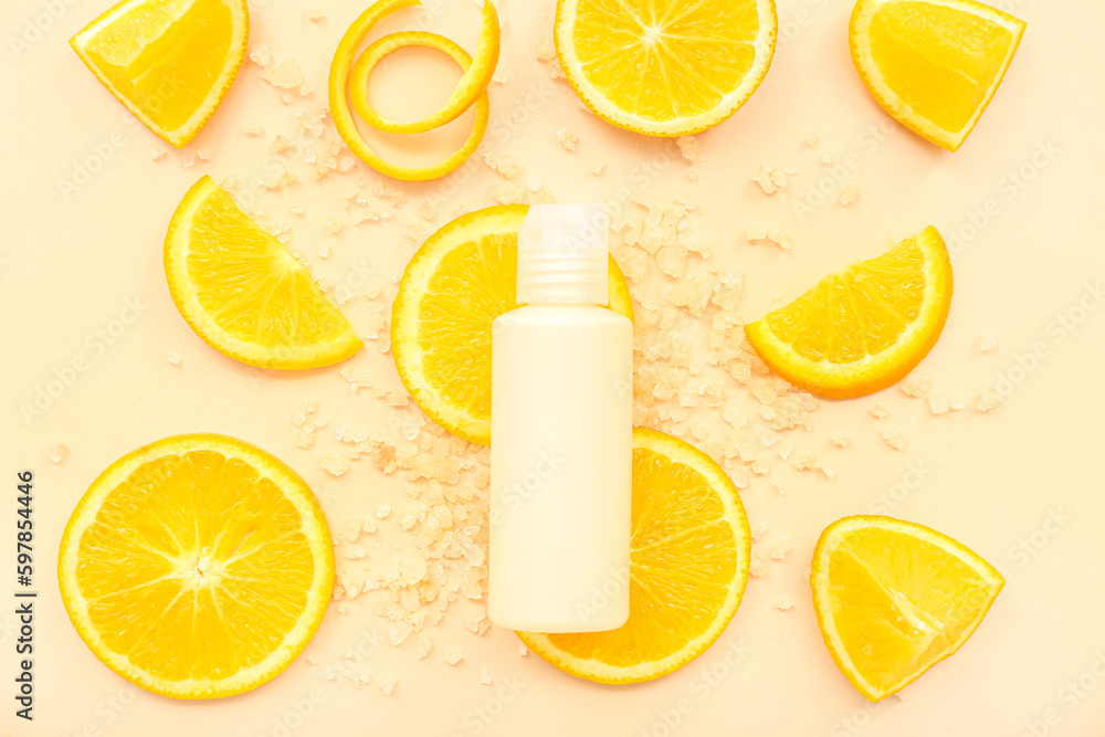 Cosmetic bottle with orange slices and sea salt on beige background