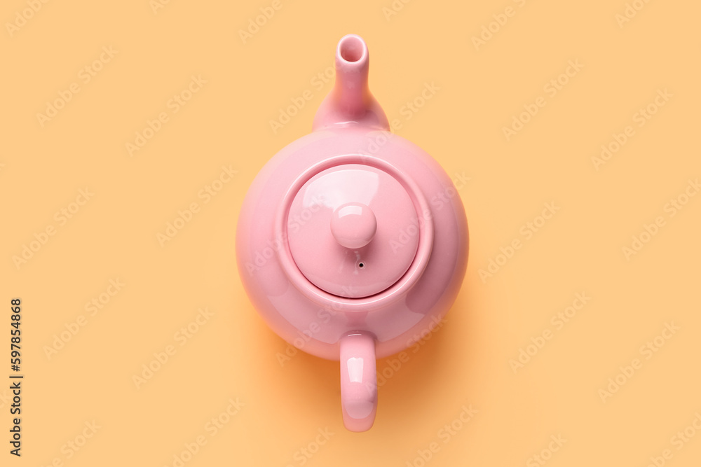 Ceramic teapot on orange background