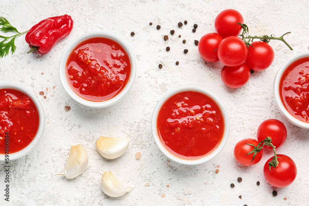 Bowls with tasty tomato sauce on light background