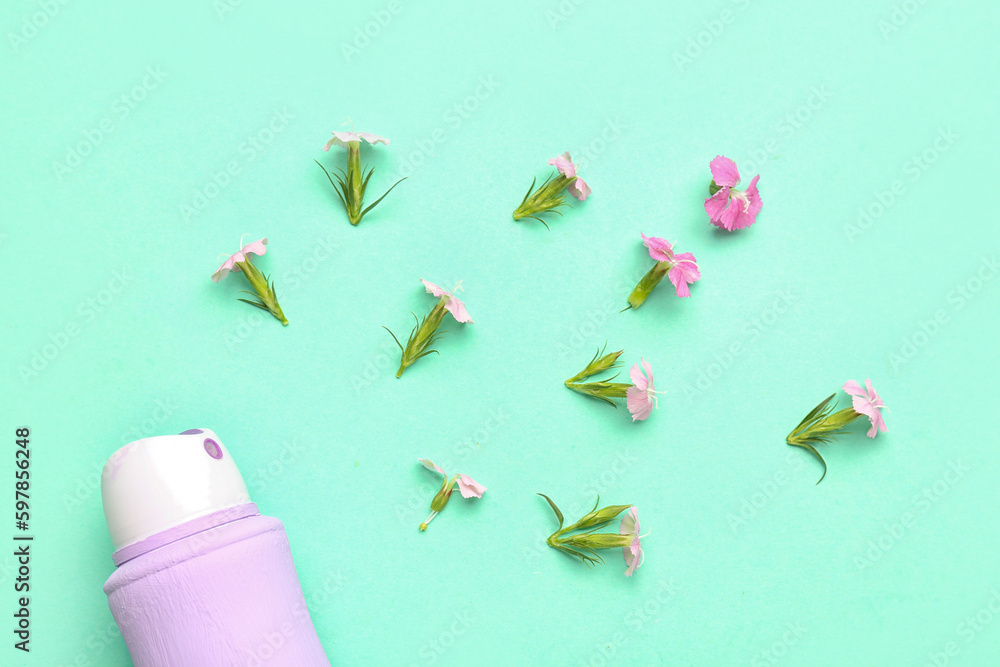 Deodorant bottle and flowers on blue background