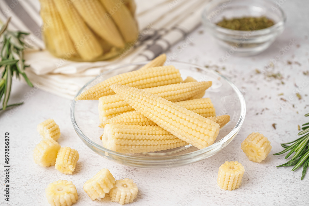 Bowl with tasty canned corn cobs on light background