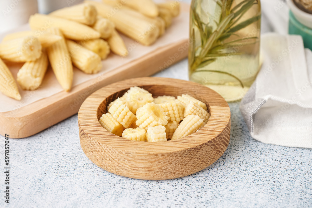 Bowl with tasty cut canned corn cobs on light background