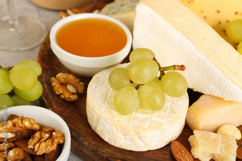 Plate with tasty cheese and grapes on table, closeup