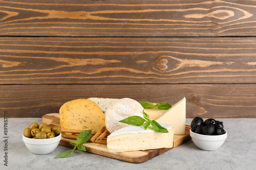 Wooden board with different types of cheese on table