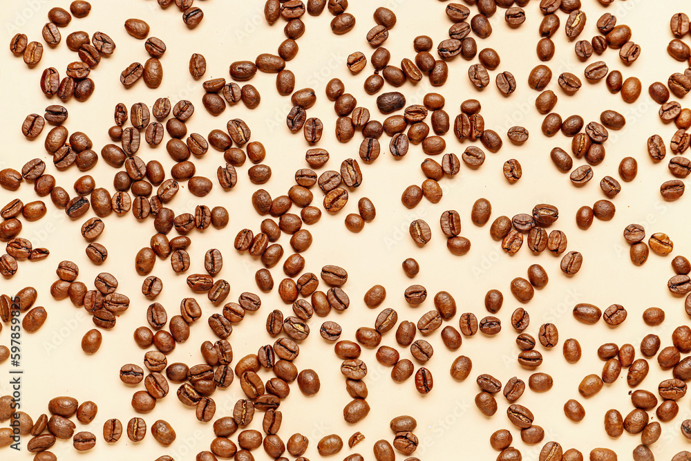 Scattered coffee beans on pale yellow background