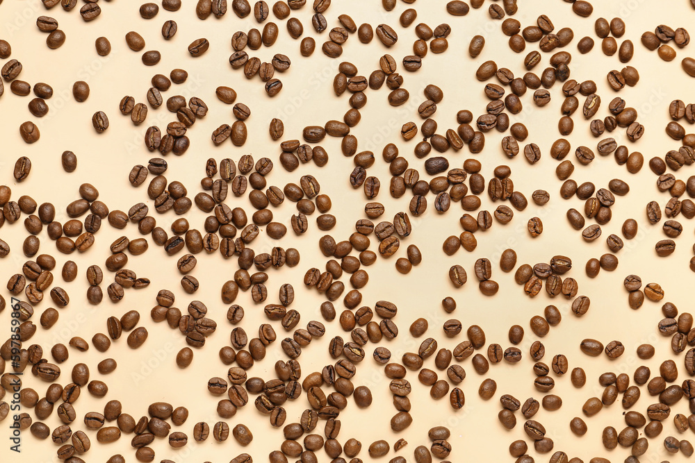 Scattered coffee beans on pale yellow background