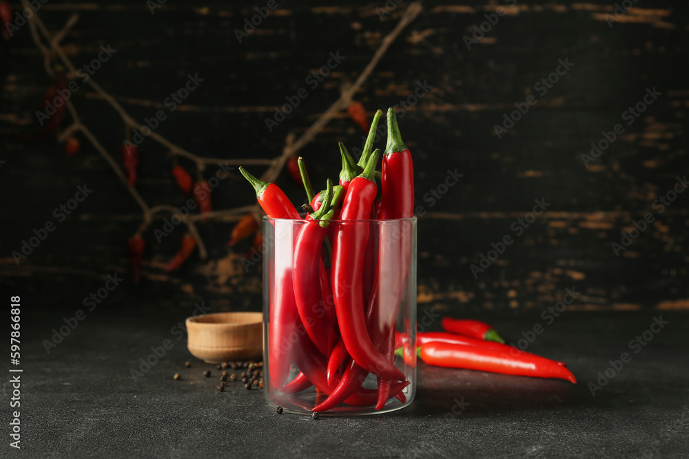 Glass of fresh chili peppers on dark background