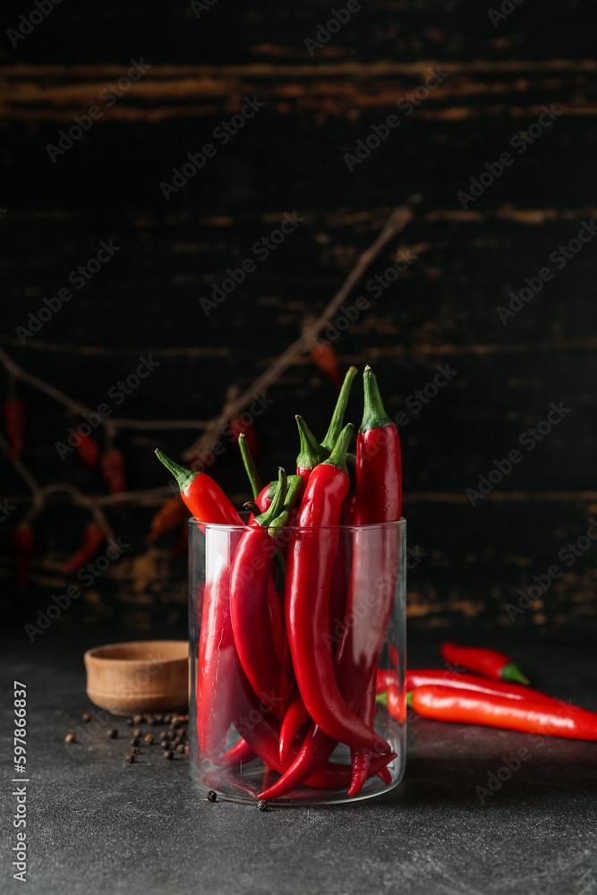 Glass of fresh chili peppers on dark background