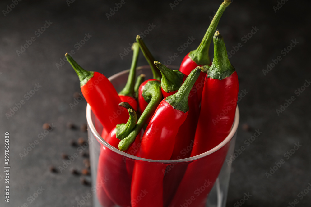 Glass of fresh chili peppers on dark background, closeup