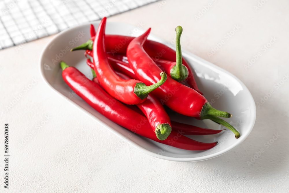 Plate of fresh chili peppers on light background