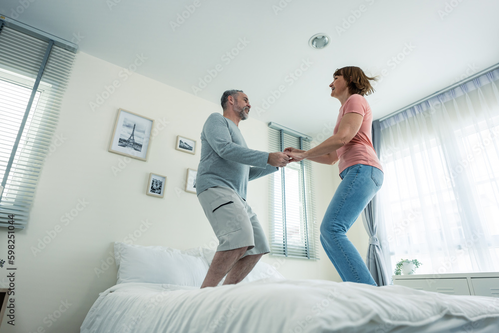 Caucasian senior couple dancing with music together in bedroom at home. 