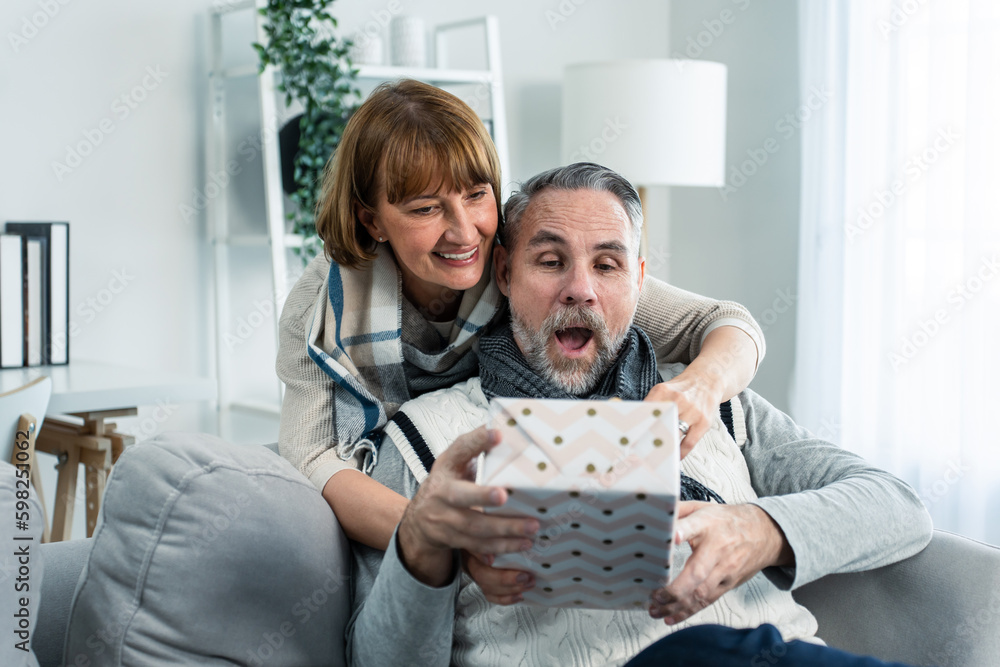 Caucasian senior elderly woman surprise her husband with birthday gift. 