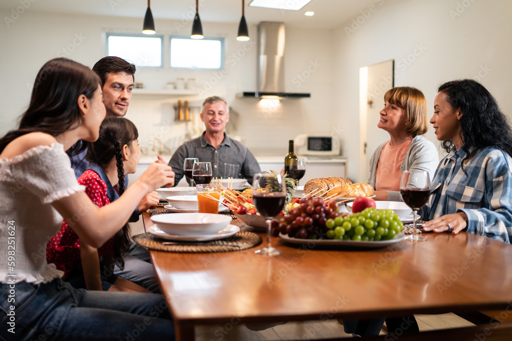 Multi-ethnic big family having dinner, enjoy evening party in house. 