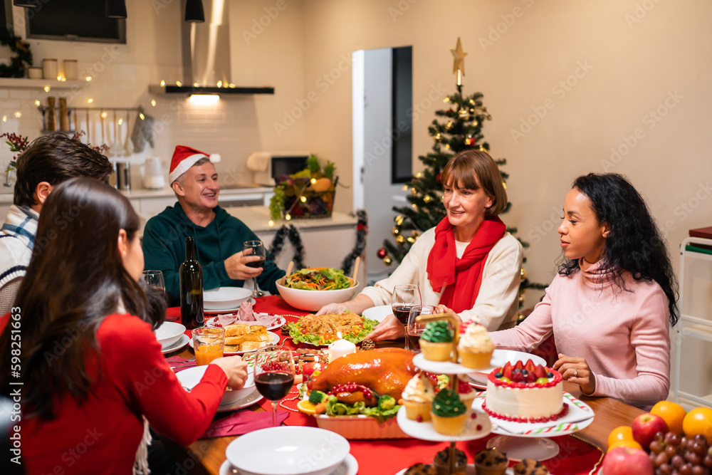 Multi-ethnic big family having dinner, enjoy evening party in house. 