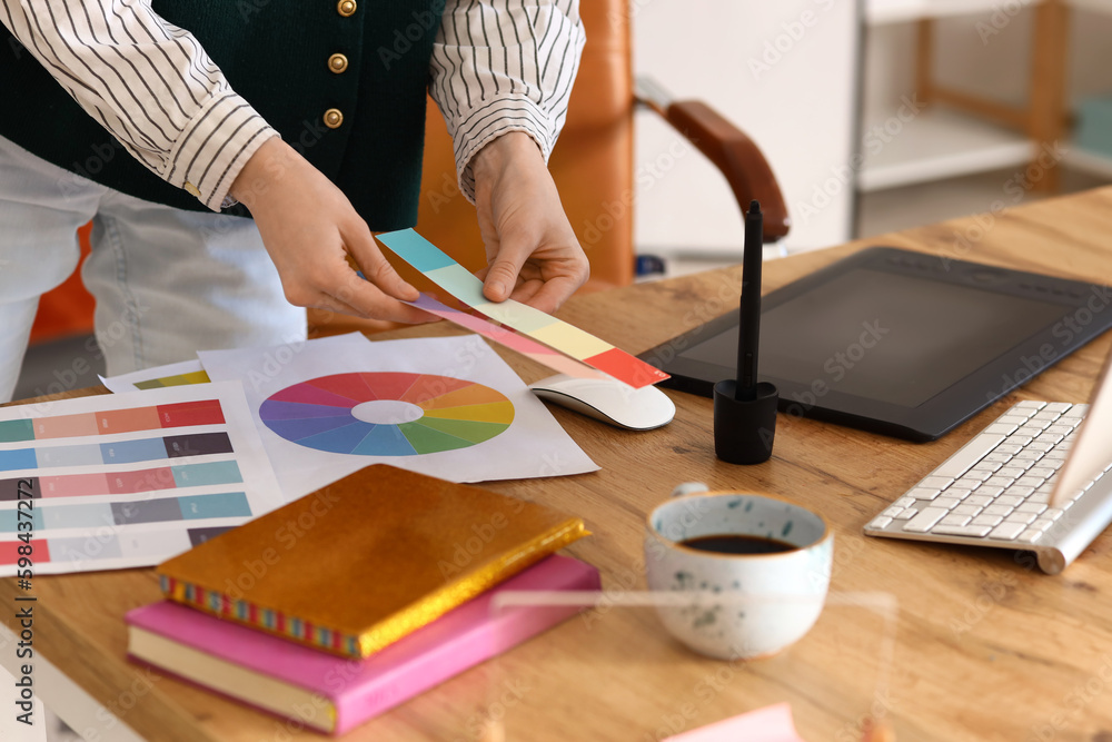 Female graphic designer working with color palettes at table in office, closeup