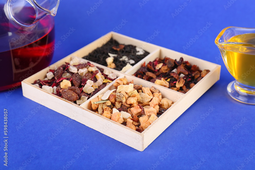 Box with different dried fruit tea on blue background