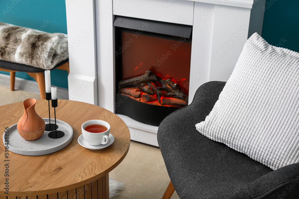 Coffee table with cup of tea, jug and candles in living room