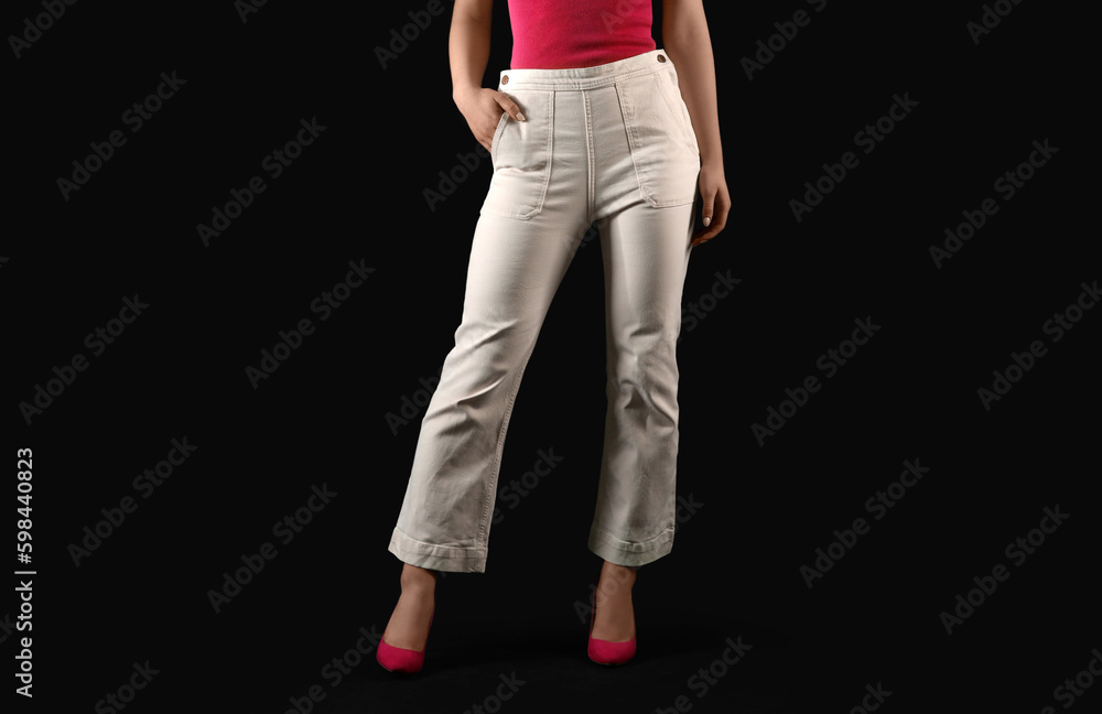 Young woman in white jeans on black background