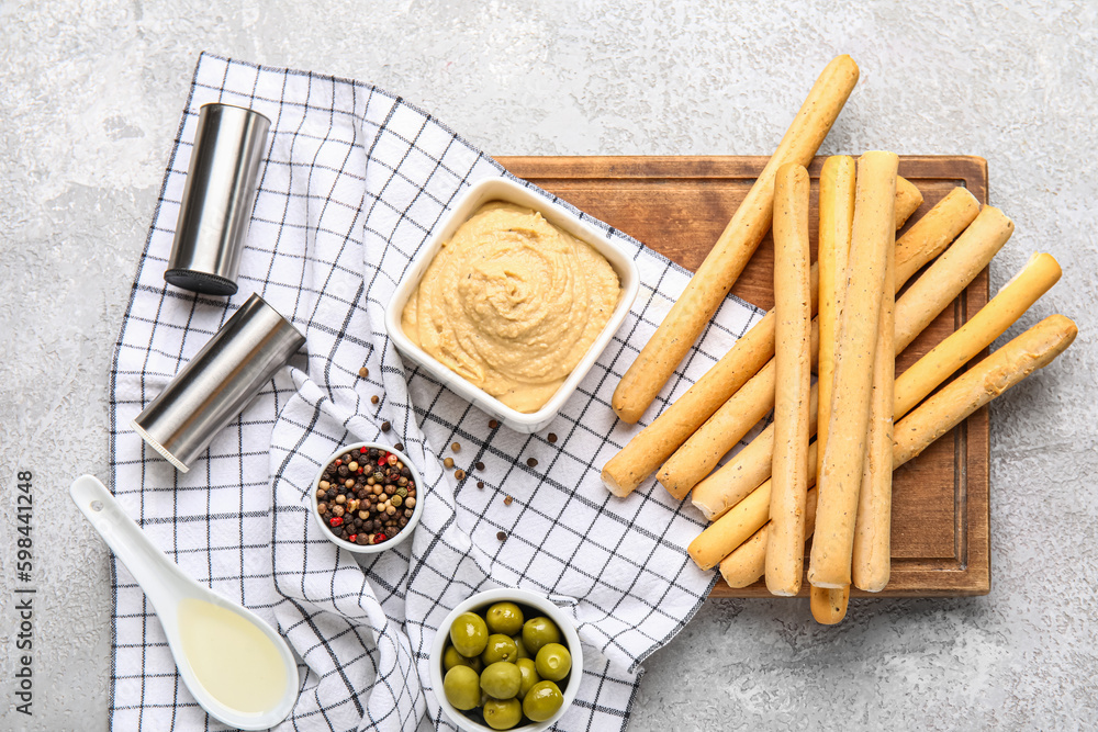 Bowl with tasty hummus and Italian Grissini on light background