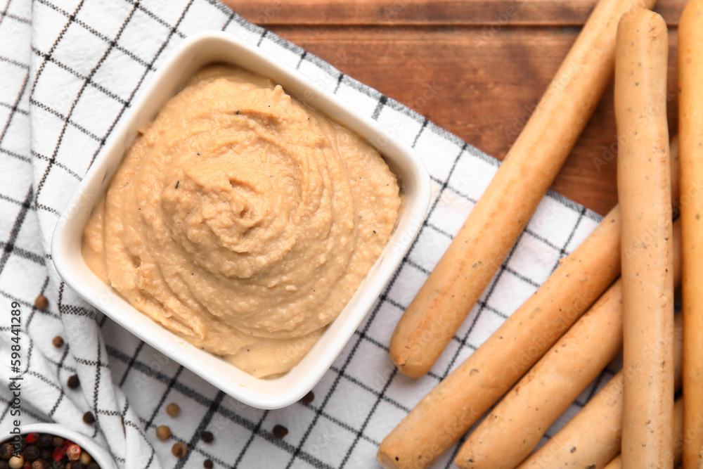 Bowl with tasty hummus and Italian Grissini on table, closeup