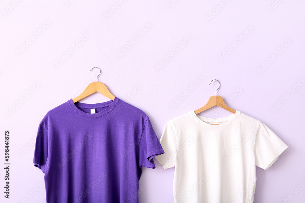 Purple and white t-shirts hanging on lilac wall