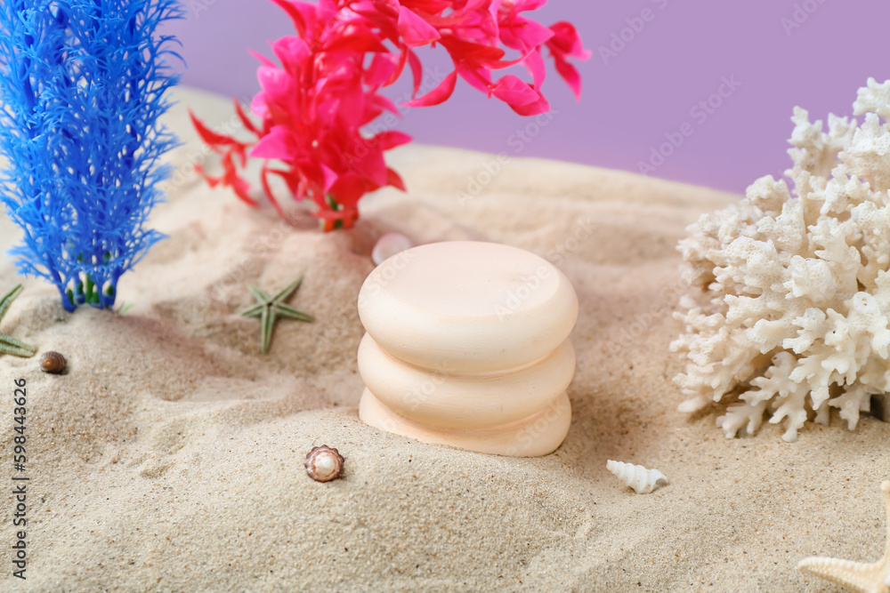 Decorative plaster podiums, seaweed, coral and starfishes in sand on purple background