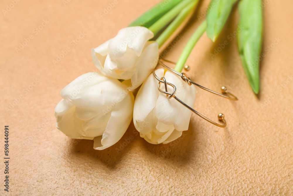 Tulips with golden bracelets on beige background, closeup