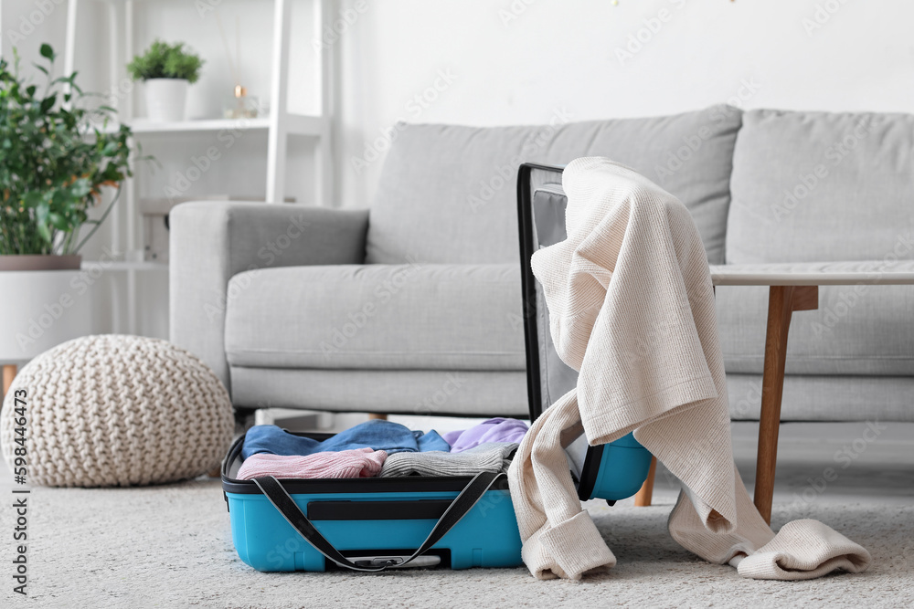 Open suitcase with clothes in interior of living room