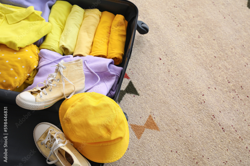 Open suitcase with clothes on beige carpet