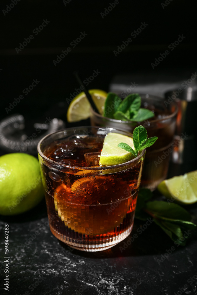 Glass of tasty Cuba Libre cocktail on dark background