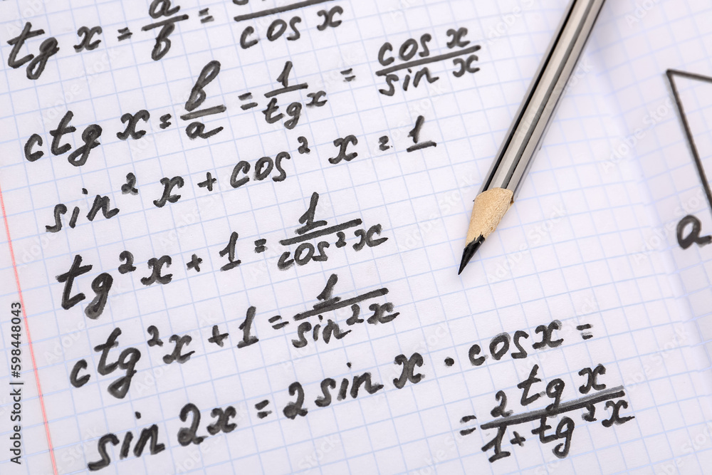 Copybook with maths formulas and pencil, closeup