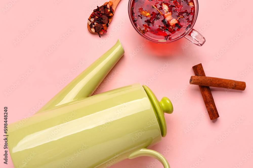 Ceramic teapot with cup of fruit tea on pink background