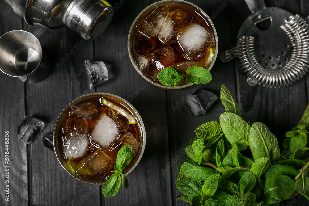 Glasses of cold Cuba Libre cocktail on dark wooden background