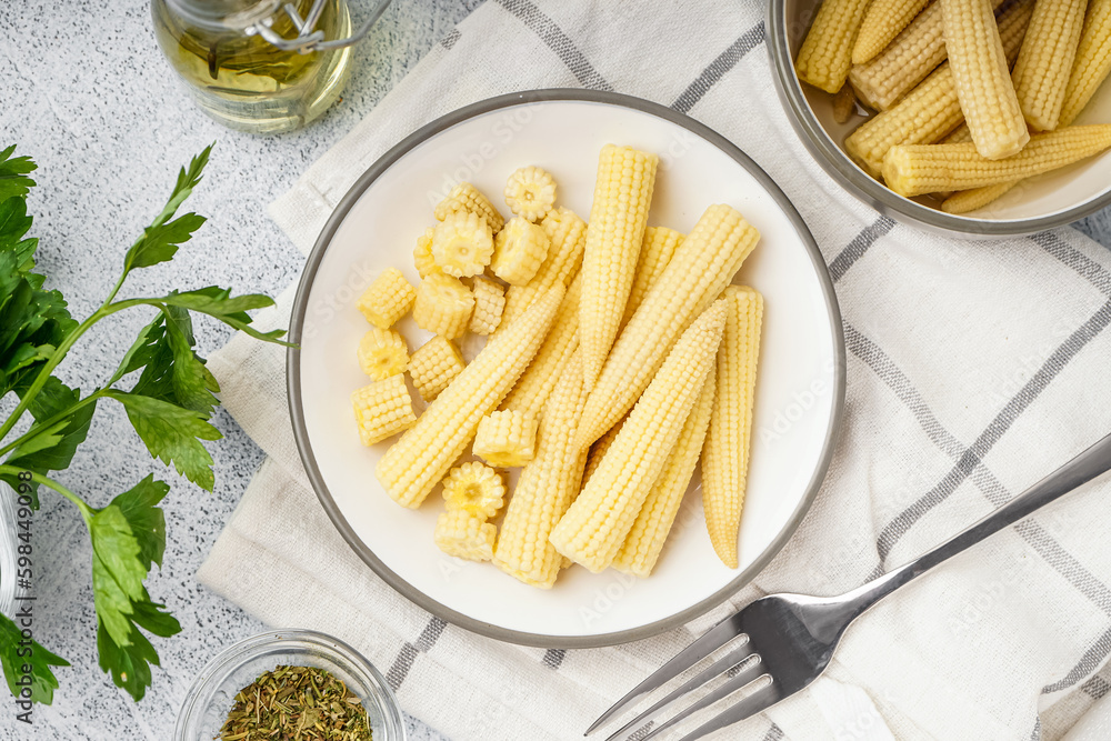 Plate with tasty canned corn cobs on light background