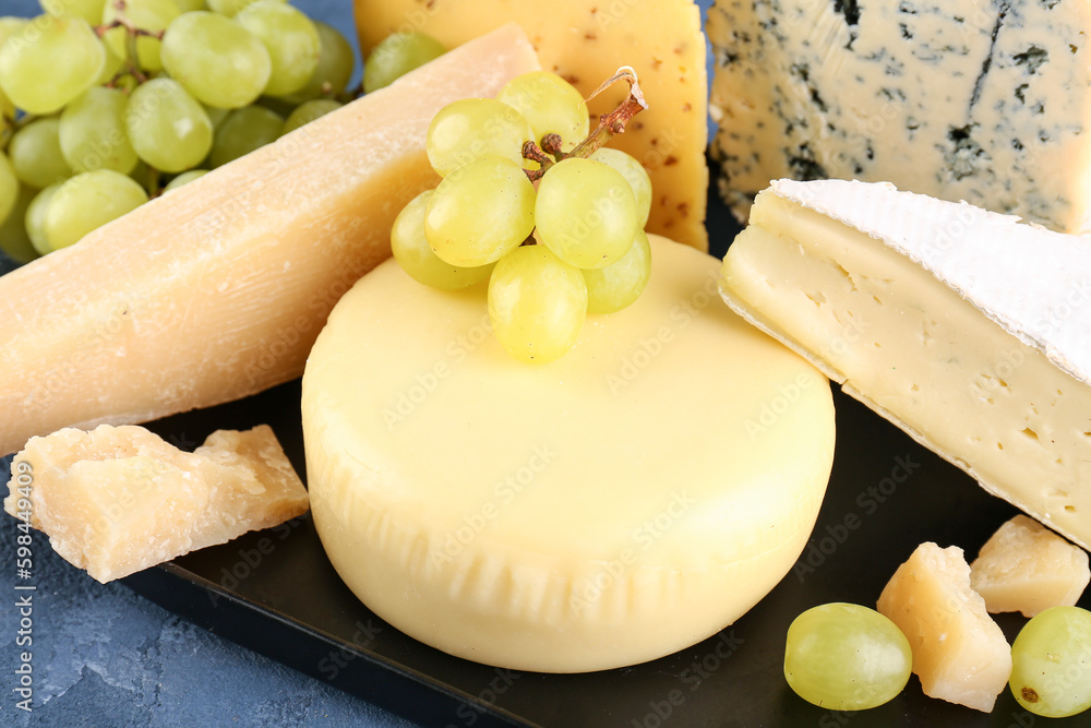 Plate with different types of cheese on blue background