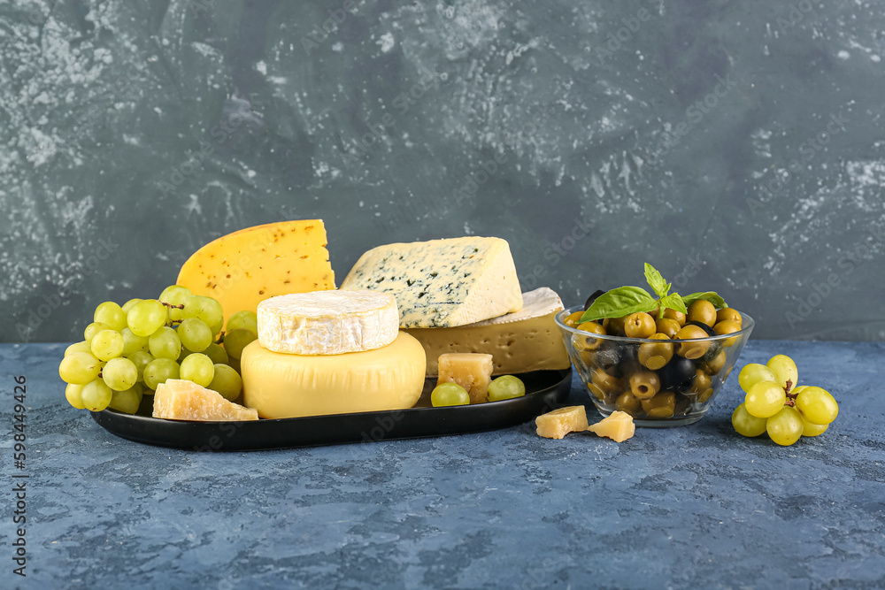 Plate with different types of cheese and grapes on table