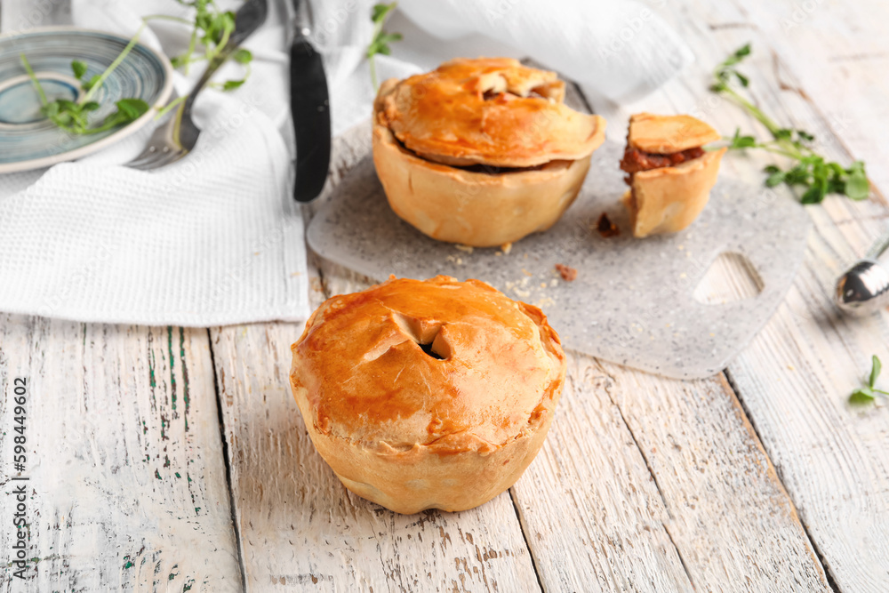 Tasty meat pot pies on light wooden background