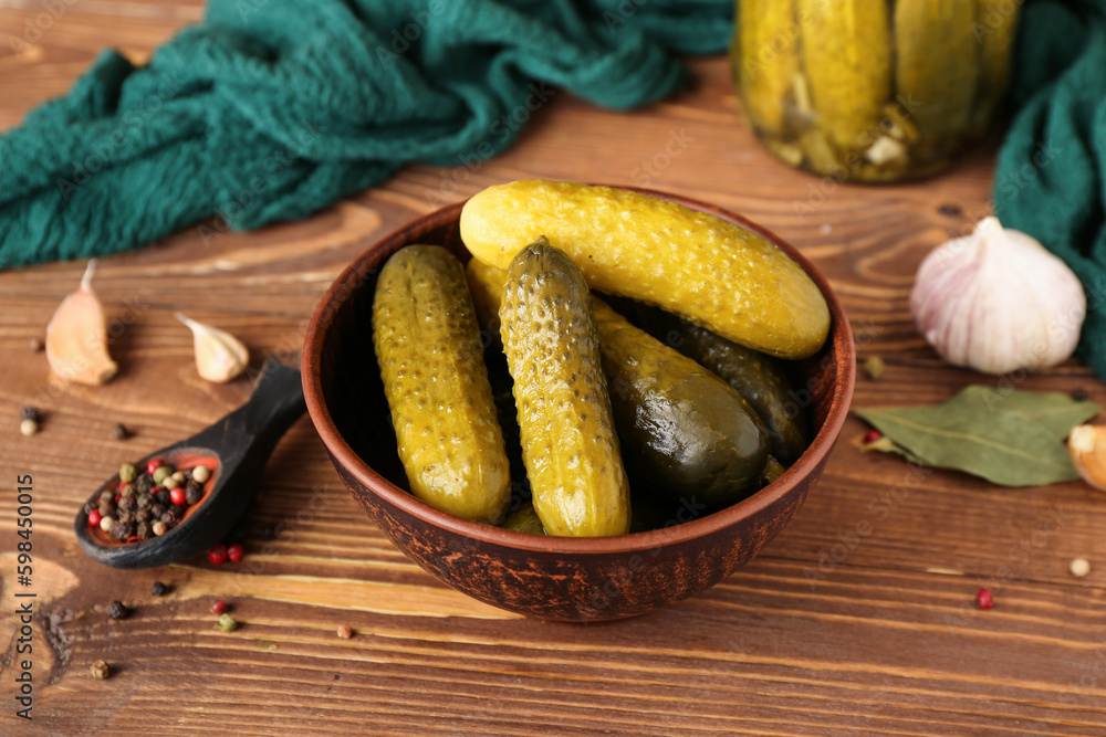 Bowl with delicious canned cucumbers on wooden table