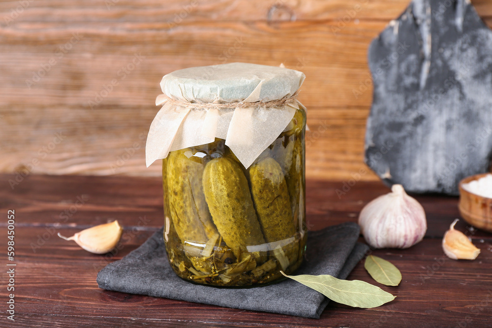 Jar with tasty canned cucumbers and spices on wooden table