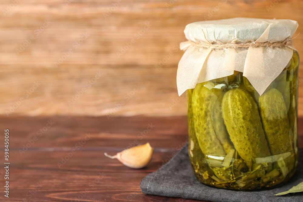 Jar with tasty canned cucumbers and spices on wooden table