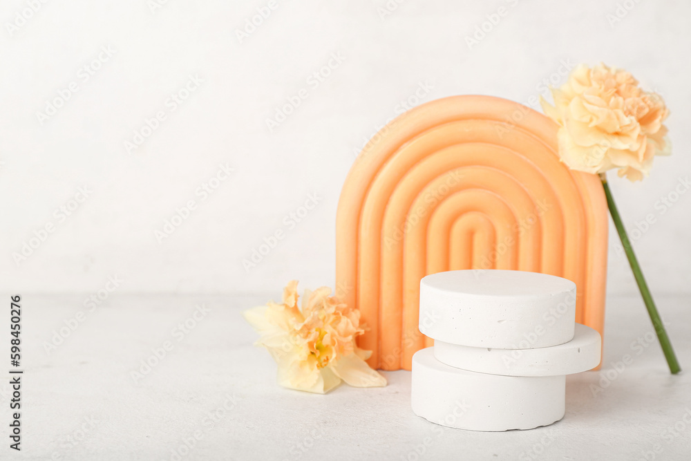 Decorative plaster podiums with daffodils on table against white wall