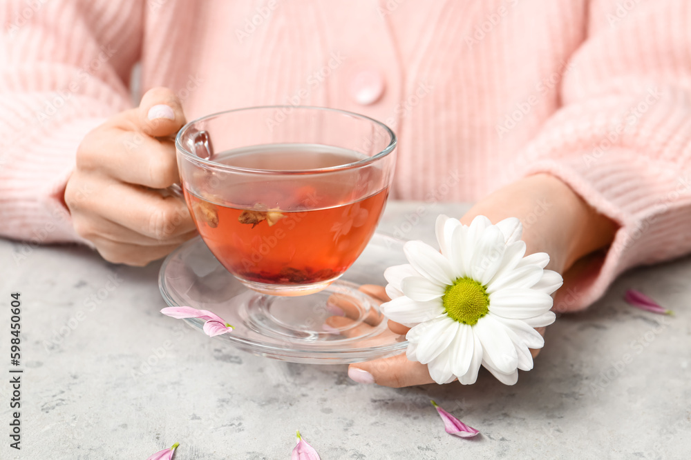 Female hands with cup of tea and beautiful chrysanthemum on marble table