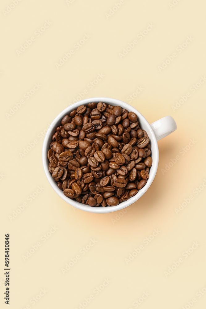 Cup with aromatic coffee beans on pale yellow background