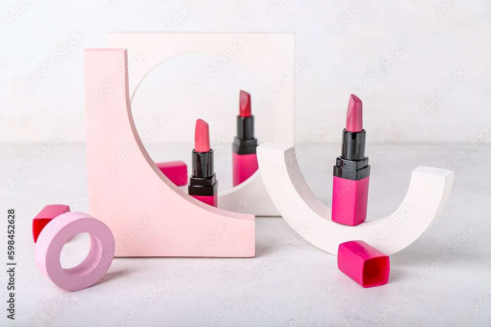 Decorative plaster podiums and lipsticks on light background