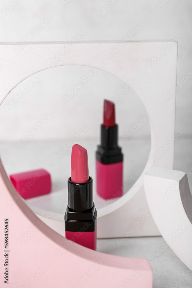 Decorative plaster podiums and lipsticks on light background