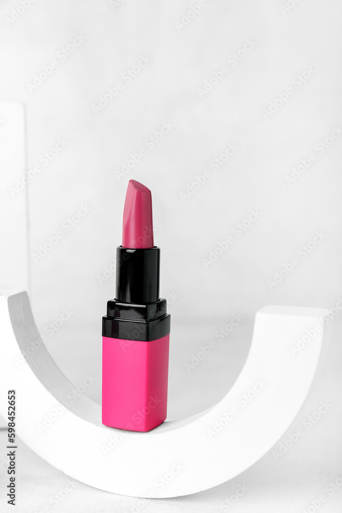 Decorative plaster podium and lipstick on light background